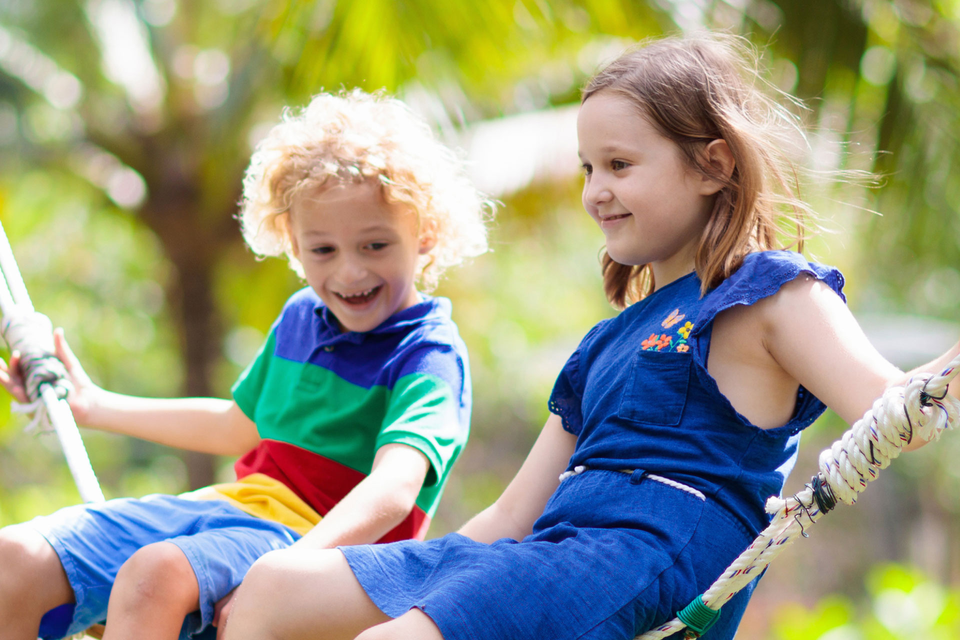 two kids sitting on a rope swing